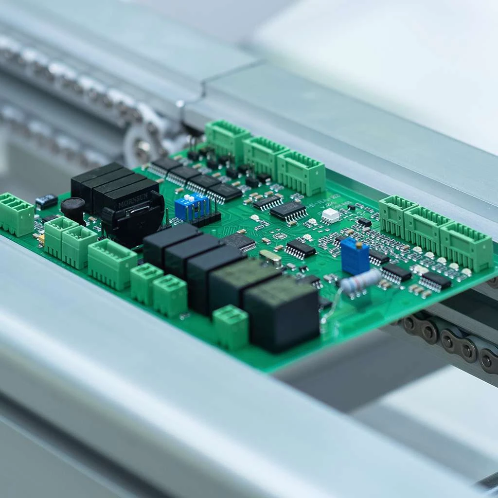 A green printed circuit board (PCB) on an automated production line, showcasing precision electronic manufacturing and high-quality component assembly for industrial applications.