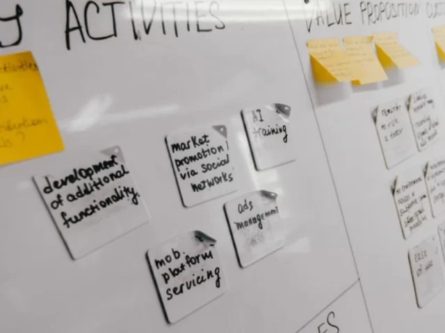 Whiteboard with sticky notes outlining project planning, key activities, and value proposition during a product development workflow.